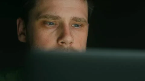 Close-up of a young freelancer working on a laptop in the evening. The Stock Footage 312984989