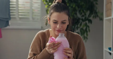 Close-up of young girl doing housework and washing clothes. Woman opens bottle 库存影片 218315277