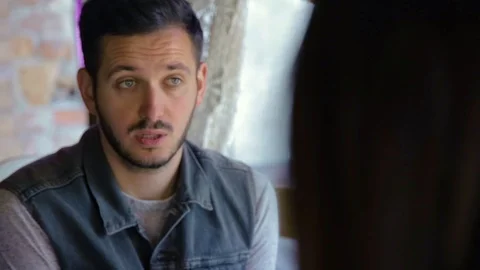 Close-up of young good-looking serious Caucasian man with beard sitting at table Video stock 108853229