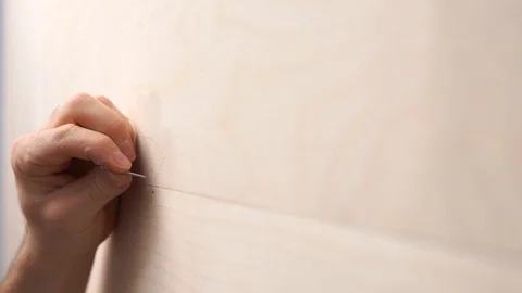 Close-up of a young guy hammering nails into plywood using a hammer. 库存影片 126317711