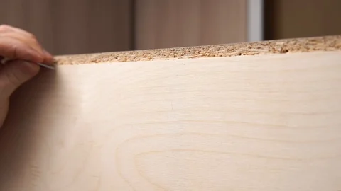 Close-up of a young guy hammering nails into plywood using a hammer. 库存影片 126837721
