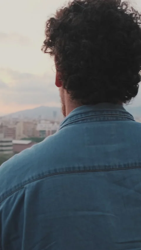 Close-up of young guy is standing on the balcony looking at the city Stock Footage 250840158