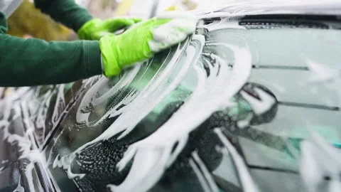 Close-up.young guy washes his car. rubs the side glass of a gray car Vidéo 164950014