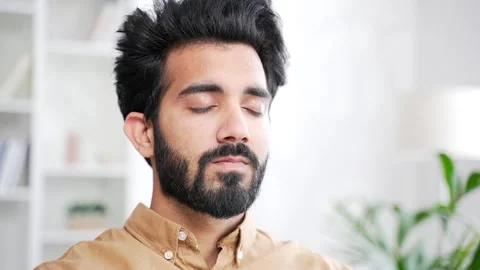 Close up. Young handsome bearded man meditating with eyes closed while sitting  Stock Footage 252216102