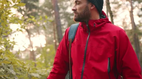 Close up of young handsome caucasian man in hat and red jacket walks in park and Stock Footage 147067623