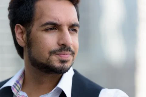 Close up of young handsome Indian man thinking outdoors in the c Stock Photos