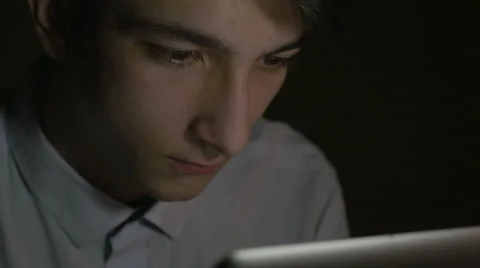 Close-up of young handsome man using tablet pc in the dark Stock Footage 58960318