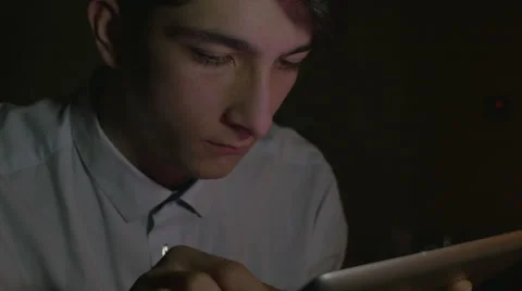 Close-up of young handsome man using tablet pc in the dark Stock Footage 58960504