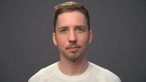 Close up young handsome man in a white sweater looking to the ca Stock Footage 70485960