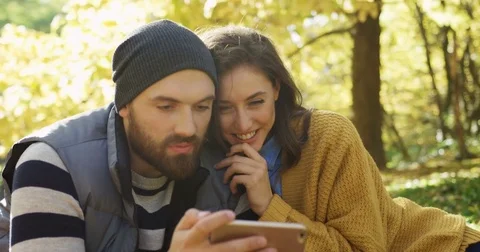 Close up of young happy couple looking at the smart phone screen and hugging in Stock Footage 82513755