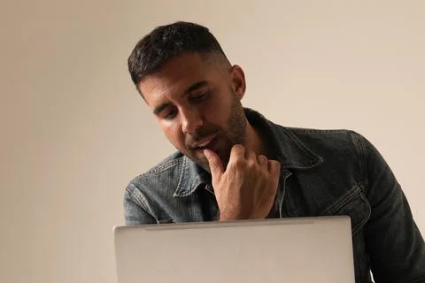 Close-up of young Indian guy working online from home, using laptop. Mock-up. Stock Photos