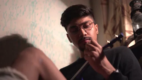 Close up of Young Indian man playing ukelele while sitting on the bed with a  Stock Footage 147237484