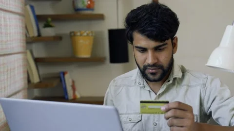 Close up of young Indian man using laptop at home and holding credit card. Stock-Footage 155575838