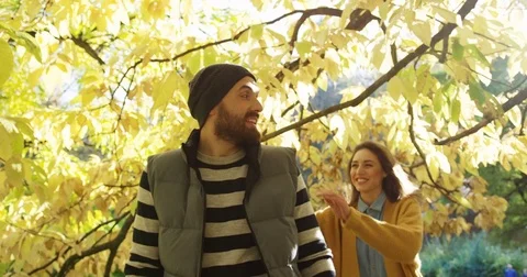 Close up of young joyful couple having fun in the yellow park. Woman jumping on Stock Footage 82511396