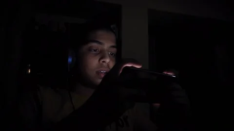 Close up Young kid playing game on mobile phone in a dark room, bright Stock Footage 164196771