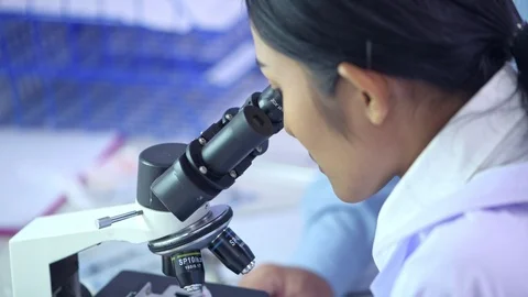 Close up on young lab scientist looking into microscope. Stock Footage 92437519