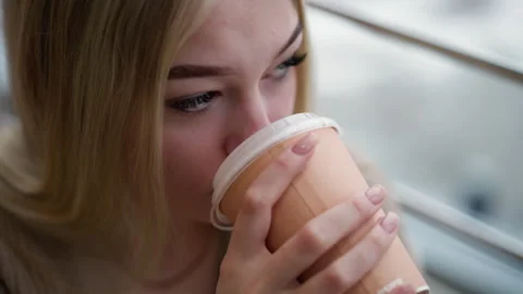 Close-up of young lady sipping coffee with focus, looking at something in urban Stock Footage 303069128