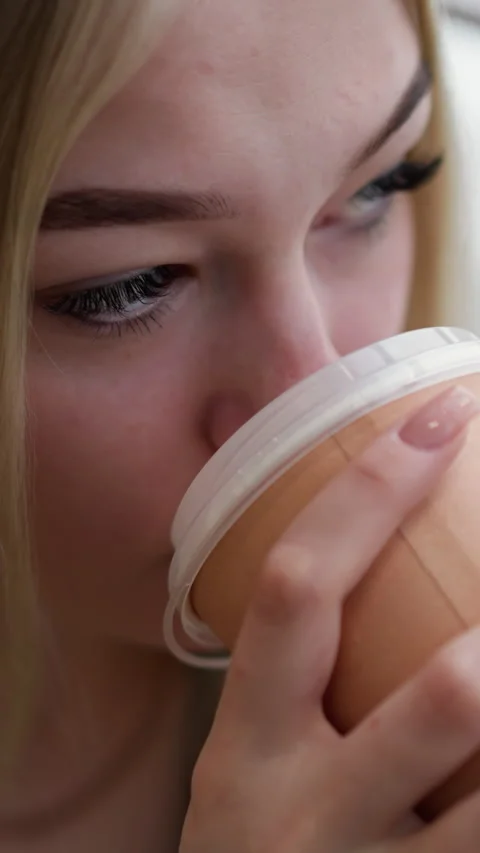 Close-up of young lady sipping coffee with focus, looking at something in urban Stock Footage 318218812