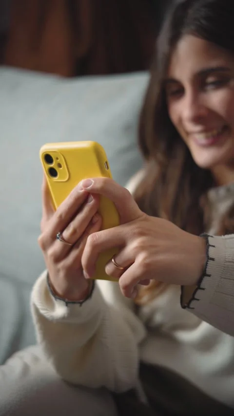 Close-up of a young Latina woman's hands using a smartphone while sitting on her Stock Footage 346162378