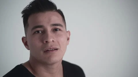 Close up of a young latino posing for the camera holds gaze and then looks up in Stock Footage 205306692