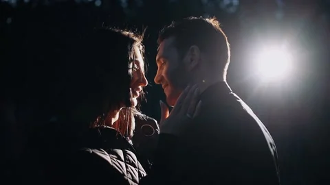 Close-up of young lovers standing face to face under the diffused light of the Stock Footage 154683976