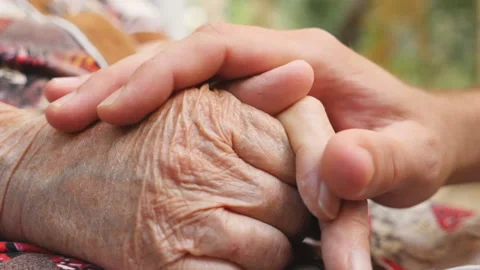 Close up of young male hand comforting an elderly arms of old woman outdoor Stock Footage
