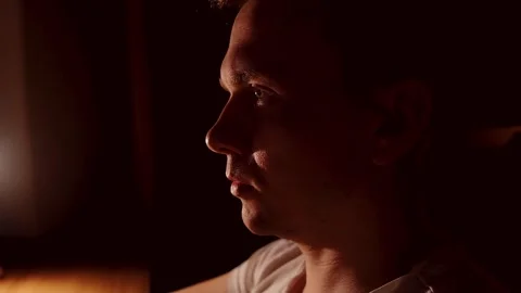 A close-up of a young male programmer looking at a screen in a dark room. Stock Footage 274096849