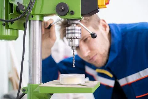 A close up young male worker using a drill machine on the factory Stock Photos