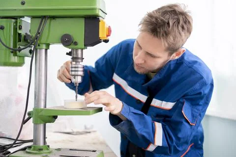 A close up young male worker using a drill machine on the factory Foto stock