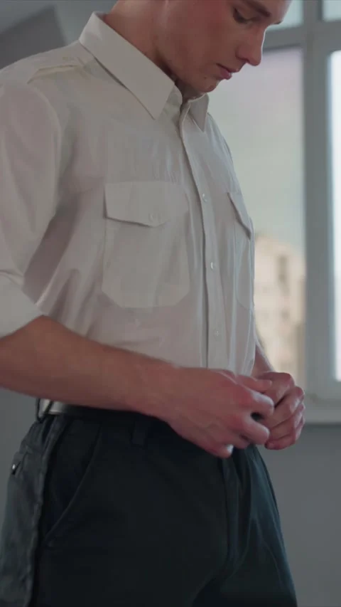 Close up of young man adjusting black leather belt with silver buckle indoors Stock Footage 343088790