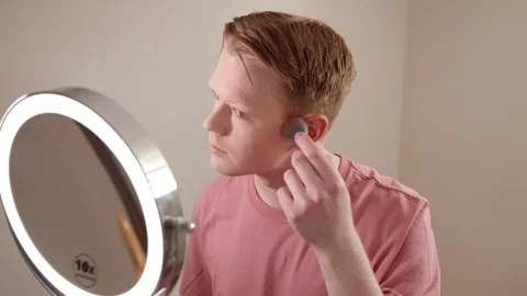 A Close-up of A Young Man Applying Blush In Front Of A Ring Light Mirror Stock Footage 309505157