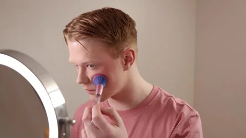 A Close-up of A Young Man Applying Blush In Front Of A Ring Light Mirror Stock Footage 309975031