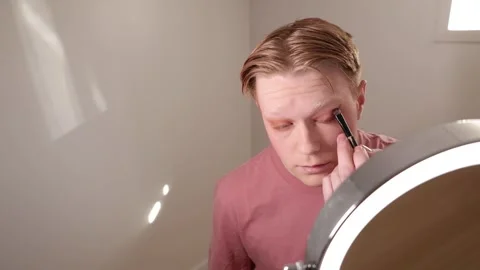 A Close-up of A Young Man Applying Eyeliner in Front of Mirror Stock Footage 309974854