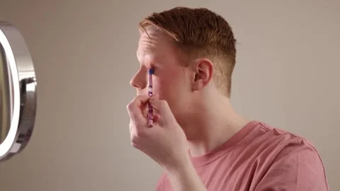 A Close-up of A Young Man Applying Eyeshadow in Front of Mirror Stock Footage 309975842