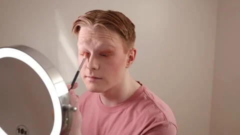 A Close-up of A Young Man Applying Eyeshadow in Front of Mirror Stock Footage 309976856