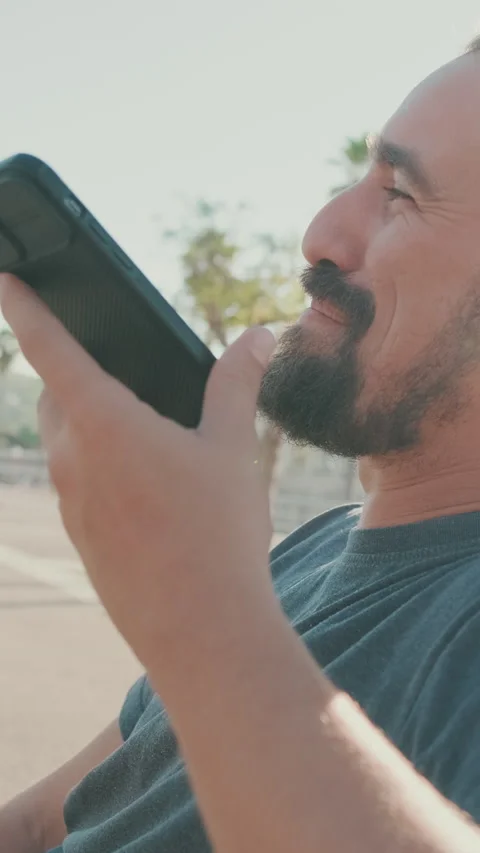 Close-up of young man with beard sitting on bench talking on cellphone on Stock Footage 226921266