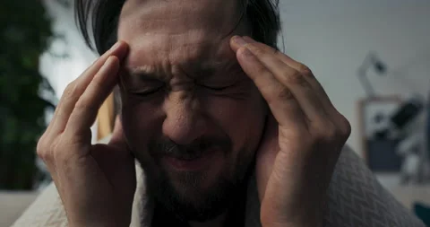 Close-up of young man with beard who is sick. Brunette has severe headaches. He Stockbeeldmateriaal 218330968