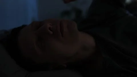 Close-up of a young man in bed yawning, feeling sleepy, turning off the light, a 스톡 동영상 296056741