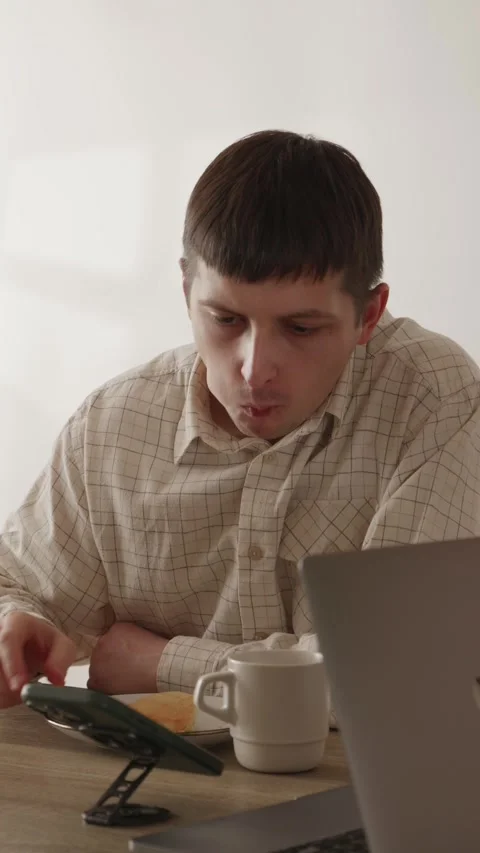 Close up of a young man biting a sweet pastry bun during work break Stock Footage 335082358