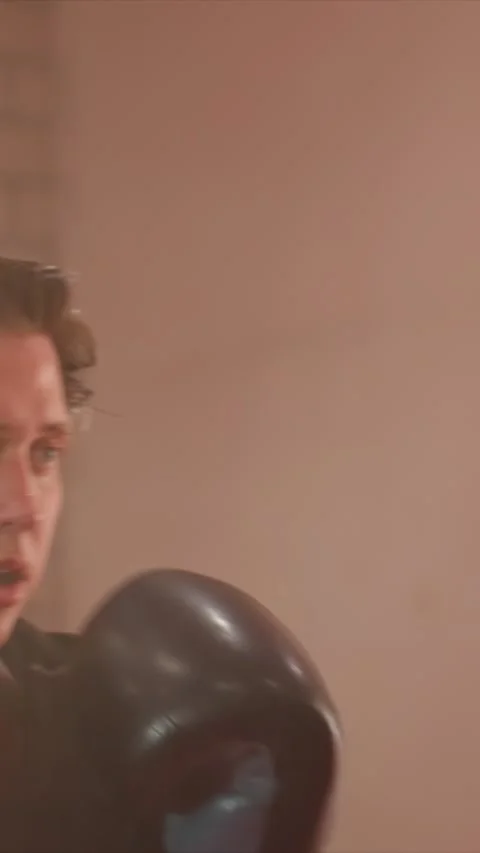 Close up young man in black boxing gloves sweating while training indoors with Stock Footage 345550330
