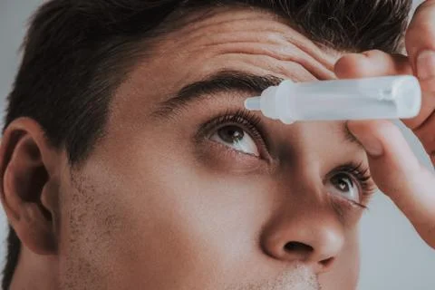Close up of young man carefully using eye drops Stock Photos