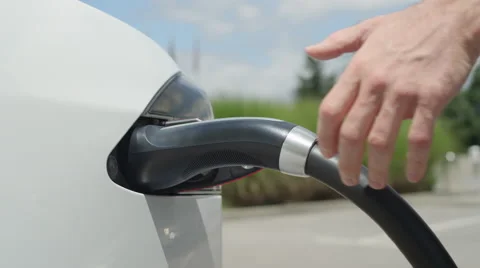 CLOSE UP: Young man charging expensive white Tesla electric car on sunny day Stock Footage