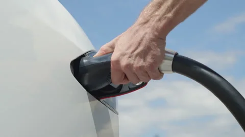 CLOSE UP: Young man charging luxury white Tesla electric car on beautiful day Stock Footage