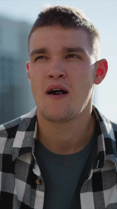 Close up of young man in checkered shirt holding red object near mouth with soft Stock Footage 345052828