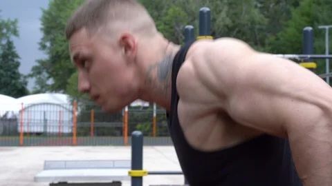 Close-up of a young man doing push-ups on the bars outdoor. Stock Footage 111701389