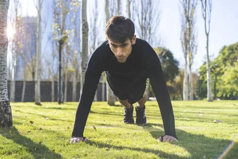Close up of young man doing push-ups on a grass in the park Stock Photos