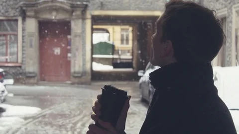 Close-up of young man drinking coffee from plastic cup on street under snowfall Stock Footage 74896484