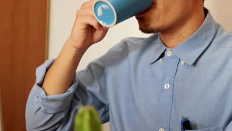 Close up of young man drinking coffee from a blue cup in the office Stock Footage 293049154