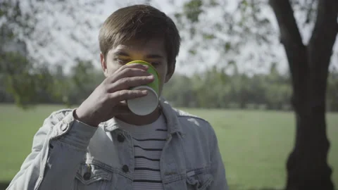 Close-up of young man drinking disgusting coffee outdoors. Portrait of Caucasian Stock Footage 145810977