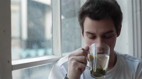 Close-up of a young man drinking tea and looking out the window Stock Footage 49775434